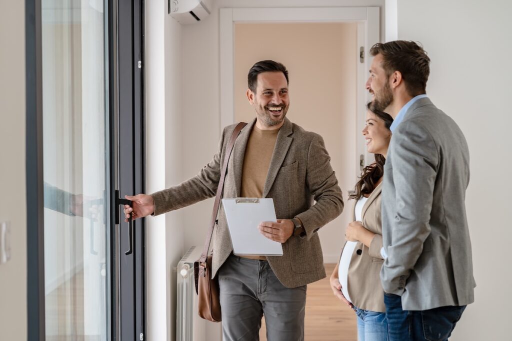 A real estate agent shows a young couple a property. Automation can help estate agents target customers better.