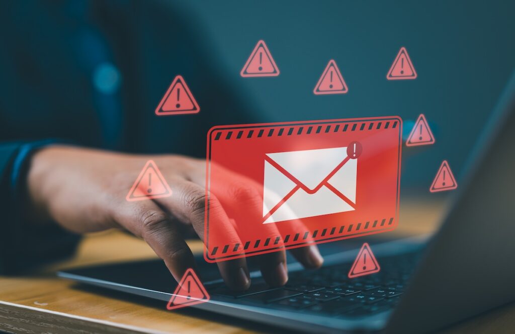 A man at a laptop receives a dangerous scam email. Email scams and spam can be serious criminal threats.